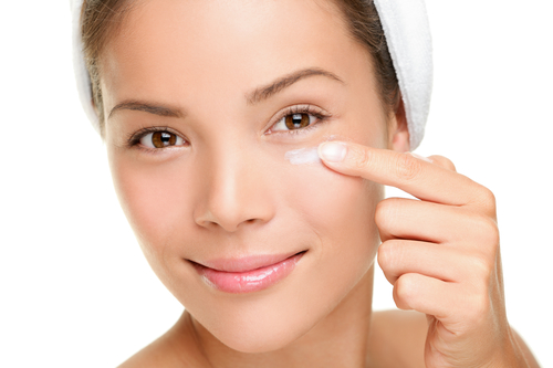 woman applying skin cream under eyes.