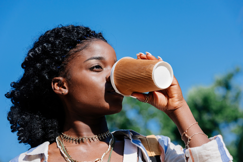 woman drinking coffee out of paper cup