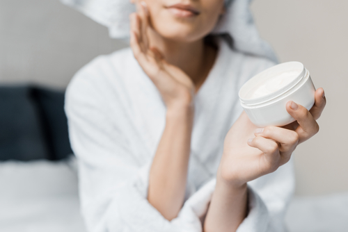 woman in robe holding skin care product