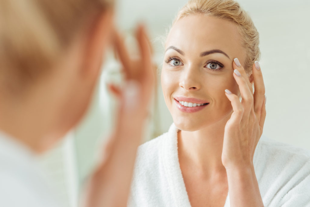 Woman inspecting anti-aging results in mirror. 