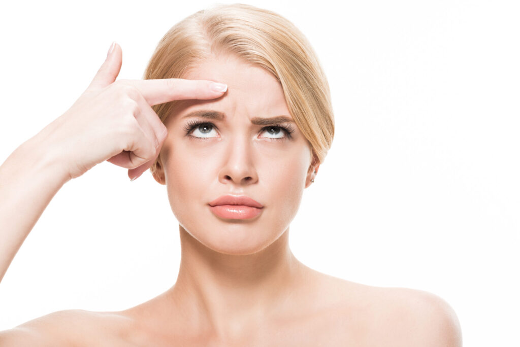Woman considering stopping Botox looking at forehead wrinkles.
